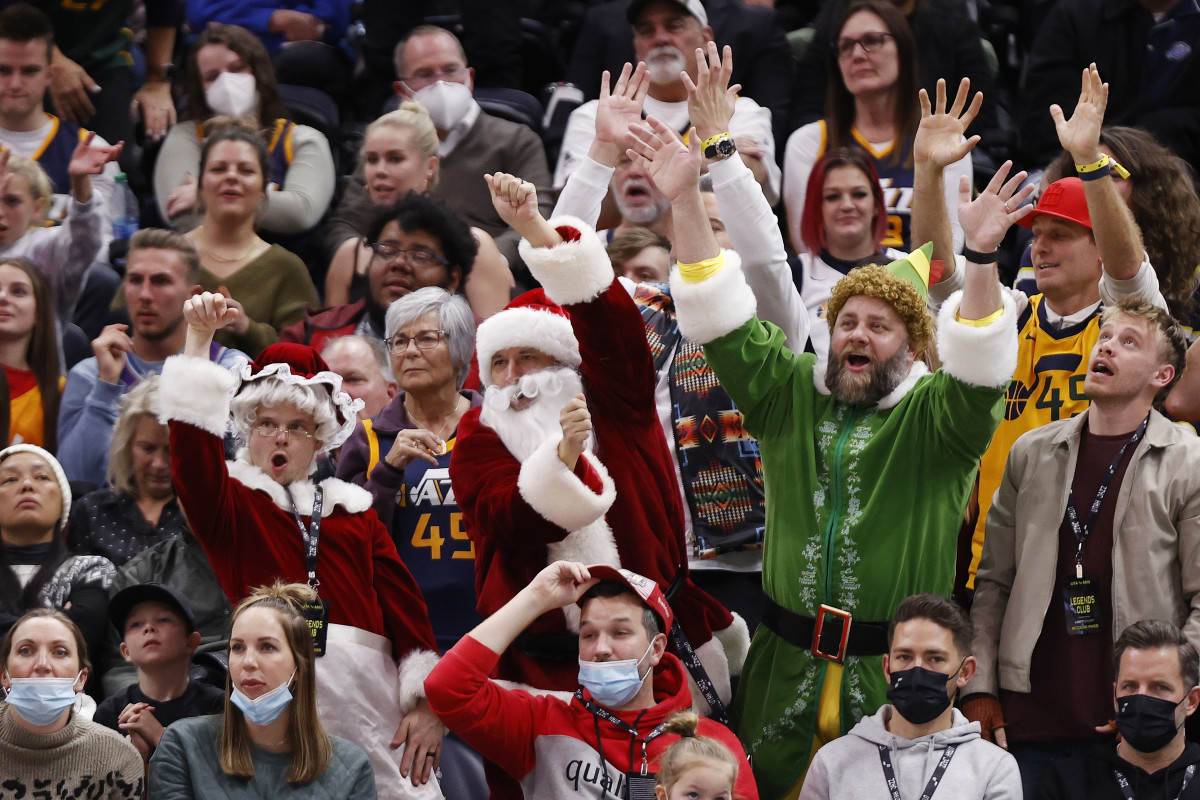Fans raise their arms in the air while dressed as an elf and santas